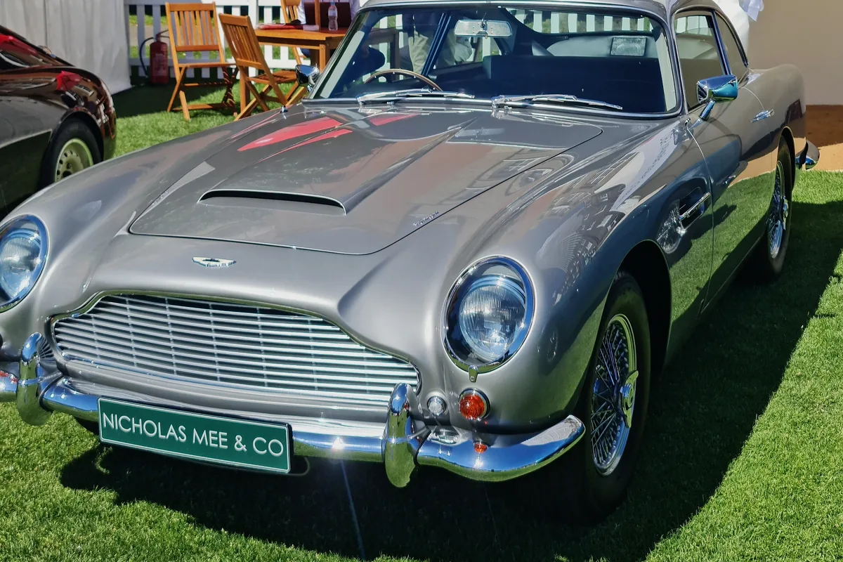 A silver 1964 Aston Martin DB5 on the lawn at a concours