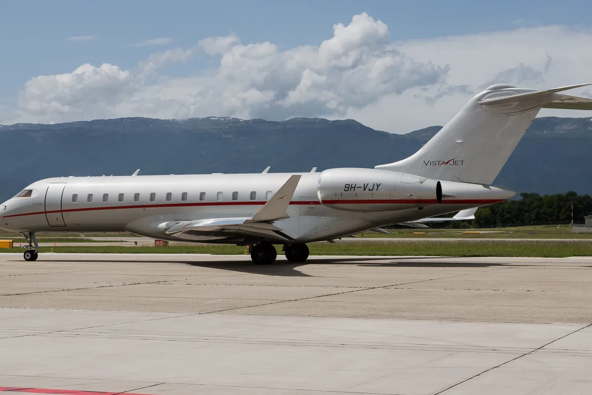 A white Bombardier Global 6000 taxiing at Geneva with mountains beyond