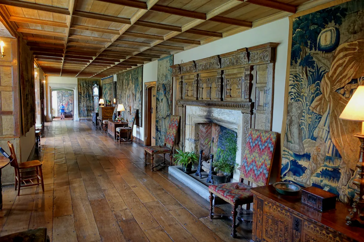 The Long Gallery at Packwood House, with wide oak floorboards, a carved overmantel and tapestries on the walls